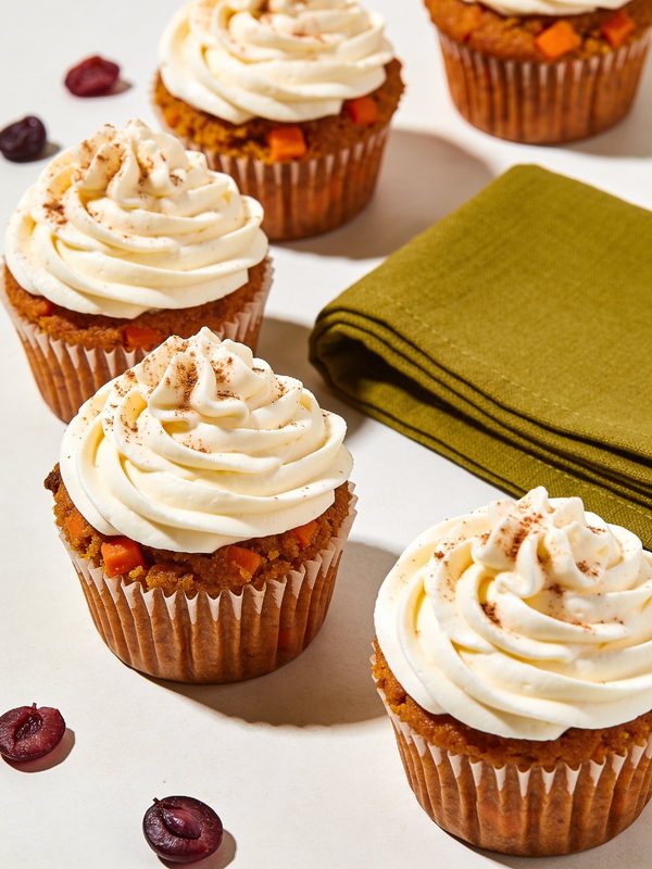 Frosting espeso de queso crema decorado sobre cupcakes de zanahoria, con un poquito de canela espolvoreada por encima.