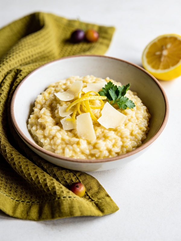 Creamy risotto topped with lemon zest, parmesan and parsley in a shallow bowl.