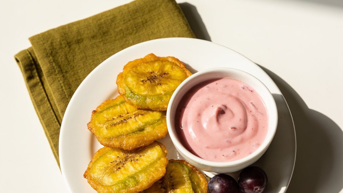 A small bowl of pink mayo-ketchup sauce next to golden tostones.