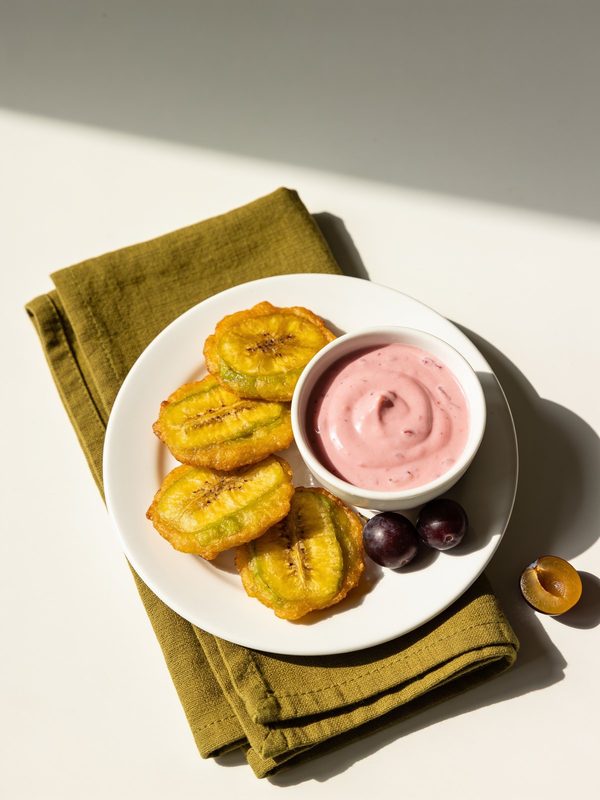 A small bowl of pink mayo-ketchup sauce next to golden tostones.