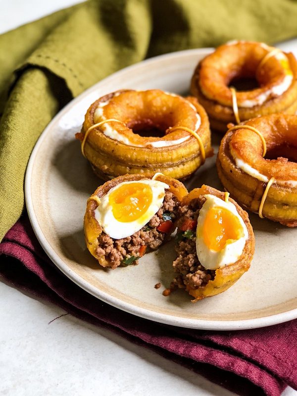 Ripe plantain rings filled with beef picadillo and capped with egg, one cut open to show the filling.